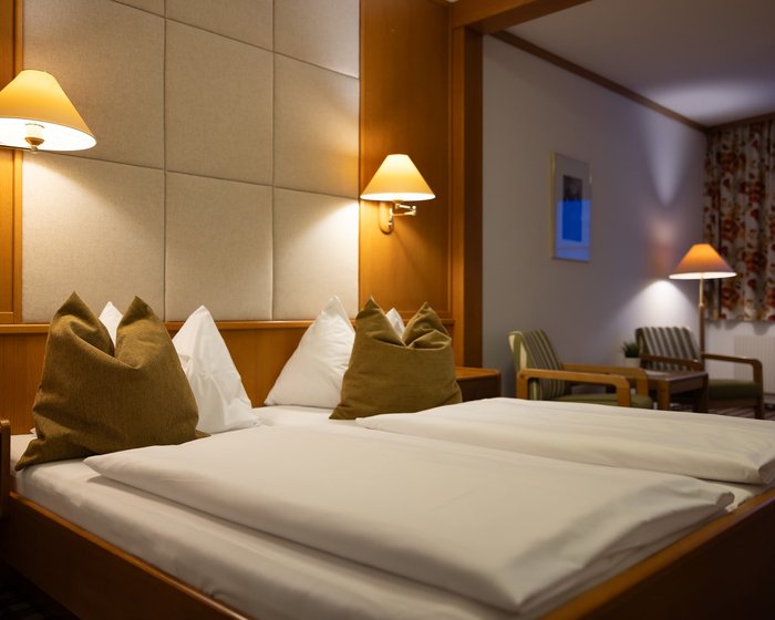Cozily furnished double room at Hotel zum Mohren with a sitting area, desk, and balcony.
