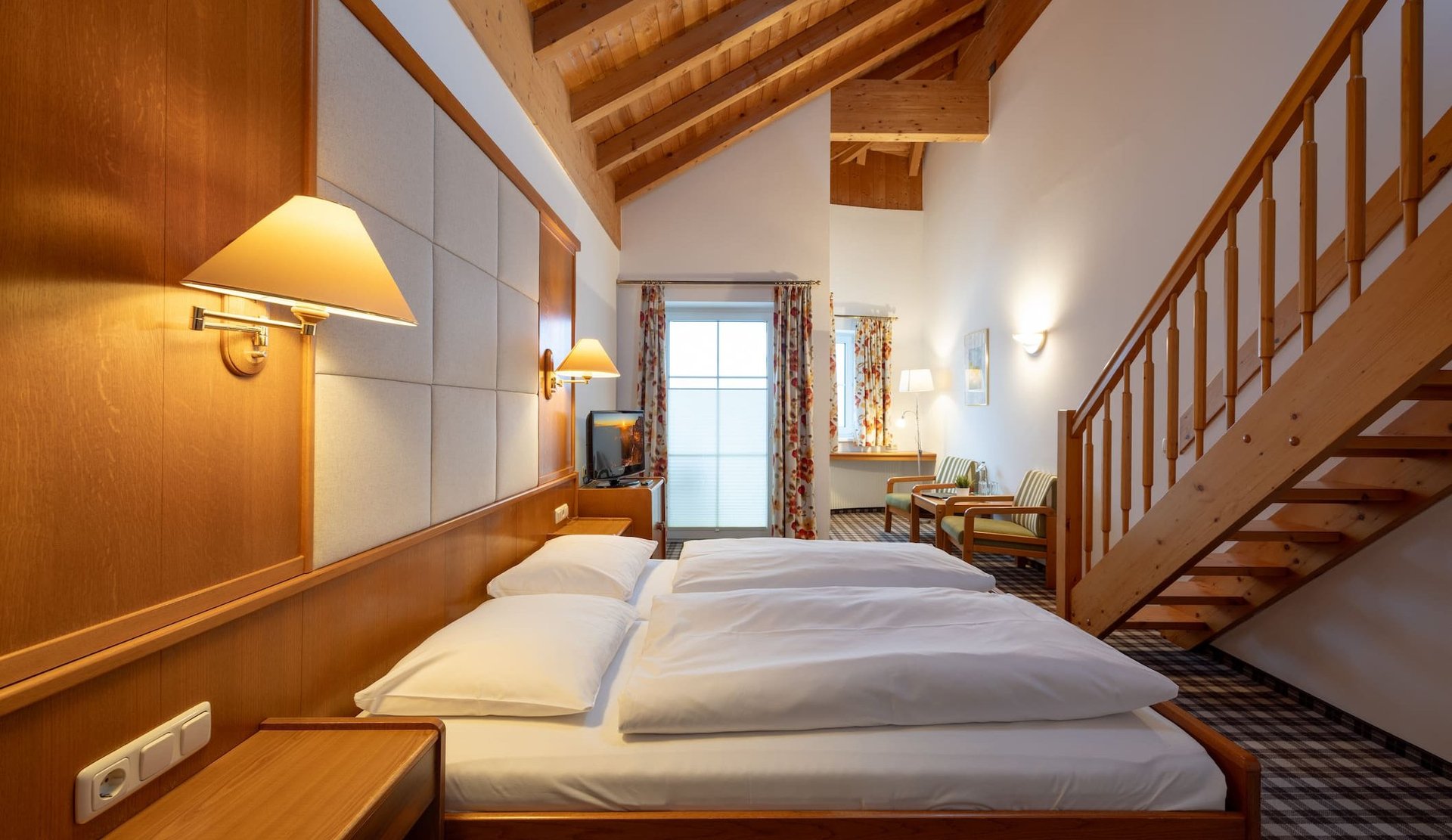 Spacious maisonette room at Hotel zum Mohren with a wooden beam ceiling and a cozy double bed.