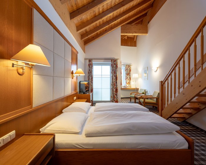 Spacious maisonette room at Hotel zum Mohren with a wooden beam ceiling and a cozy double bed.