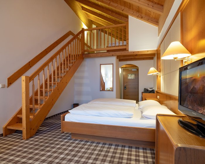 Spacious maisonette room at Hotel zum Mohren with a wooden beam ceiling and a cozy double bed.