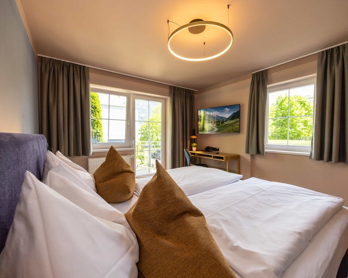 Doppelzimmer mit zwei Fenstern, großem Bett und hellem Ambiente.