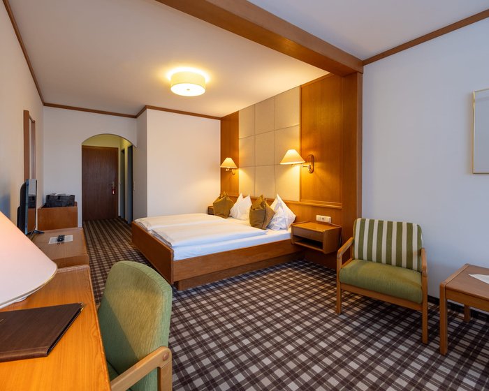 Cozily furnished double room at Hotel zum Mohren with a sitting area, desk, and balcony.
