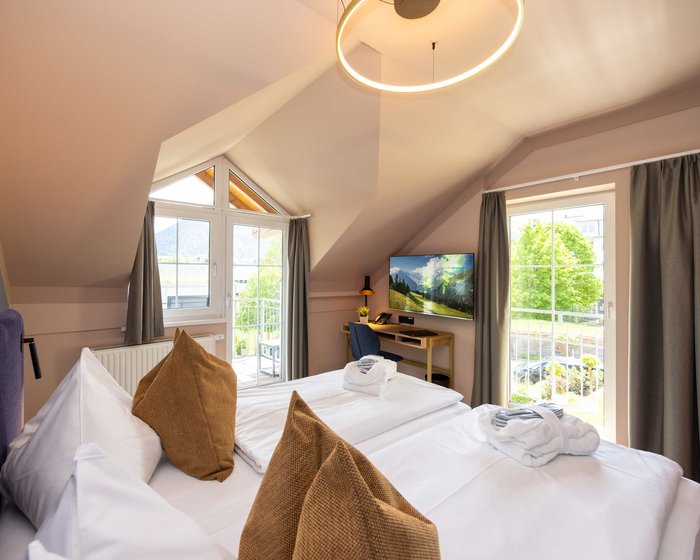 Doppelzimmer mit großem Bett, Dachschräge und Balkonblick ins Grüne.