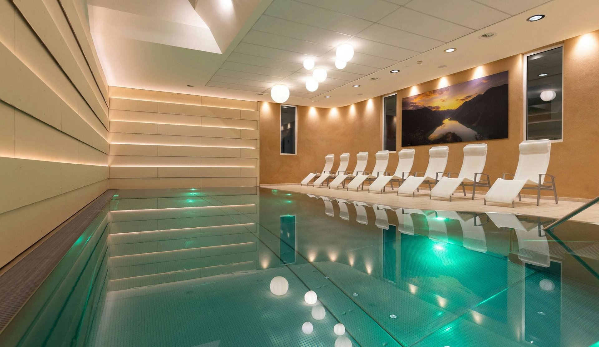 Der moderne Innenpool im Wellnessbereich des Hotel zum Mohren mit bequemen Ruheliegen am Beckenrand.