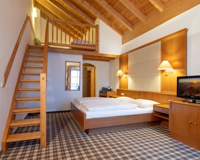 Spacious maisonette room at Hotel zum Mohren with a wooden beam ceiling and a cozy double bed.