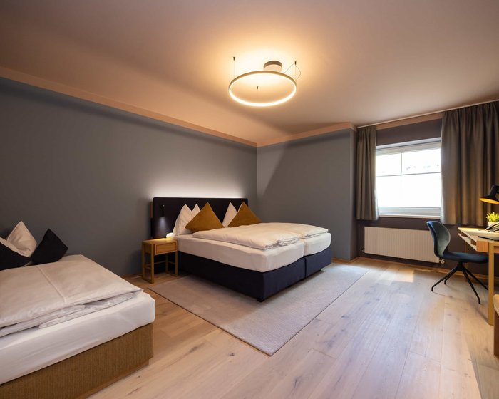 Familienzimmer Standard mit Doppelbett und kleinem Schreibtisch am Fenster.